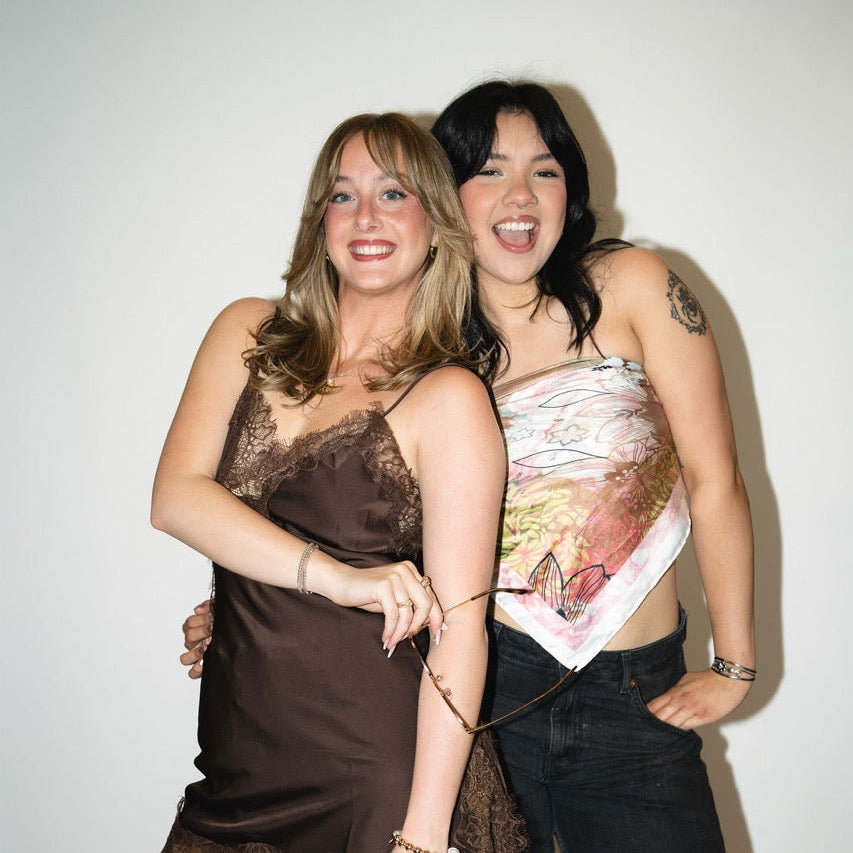 Two women posing together against a plain background